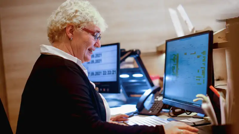 Eine Frau schaut auf zwei Computerbildschirme.
