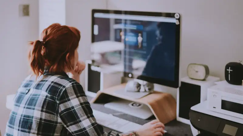 Eine junge Frau sitzt an einem Schreibtisch vor einem Computer