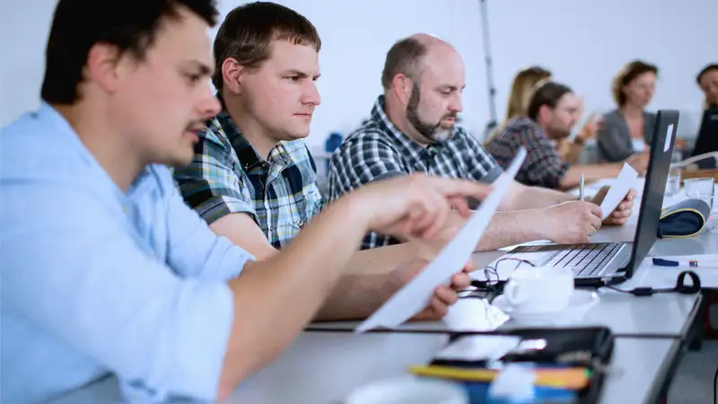 Eine Gruppe von Menschen sitzen in einem Konferenzraum und arbeiten etwas aus.