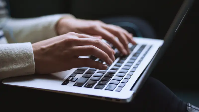 Zwei Hände, die auf einer Laptop-Tastatur tippen