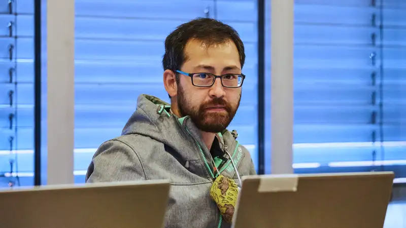 Ein Mann sitzt in einem Konferenzraum vor einem Laptop.