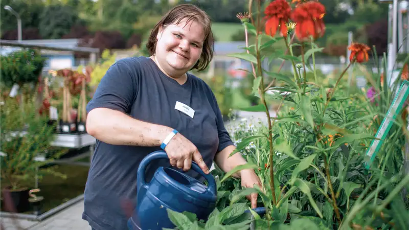 Eine Frau gießt Blumen mit einer Gießkanne