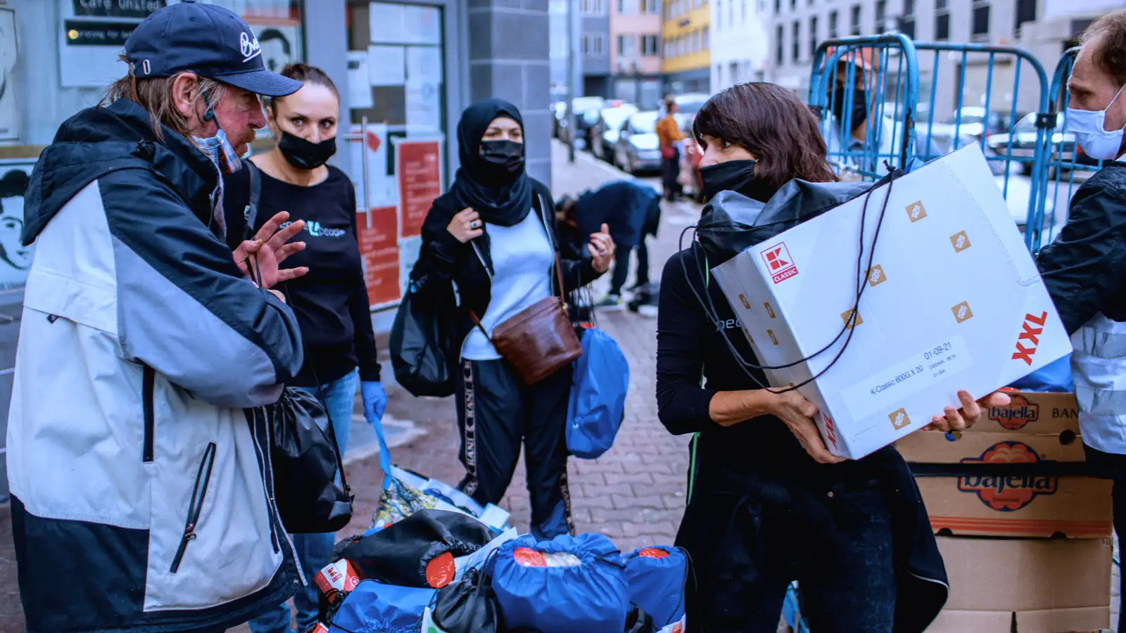 Eine Gruppe von Menschen mit Hilfsgütern mit einem obdachlosen Mann