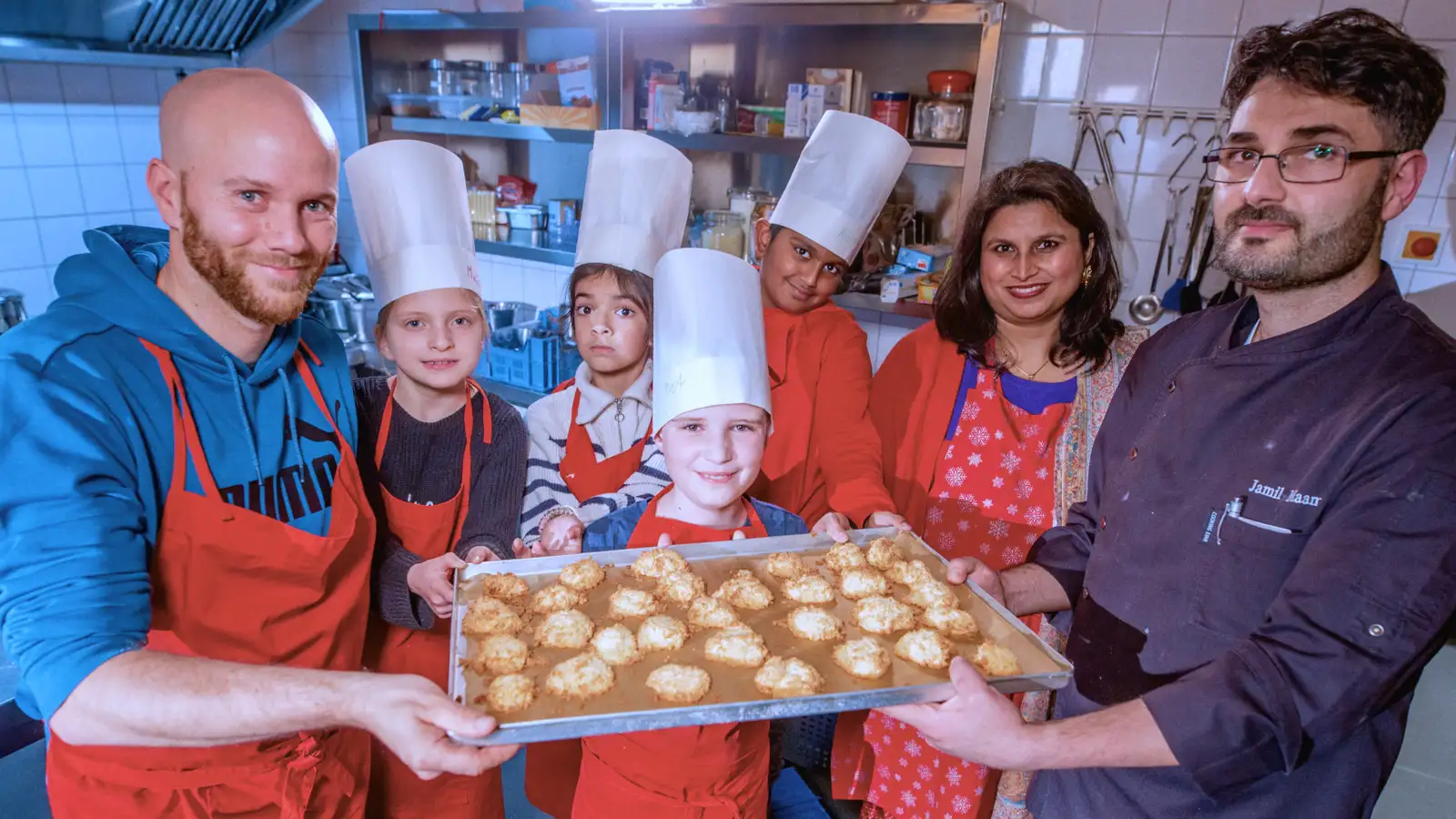 Mehrere Erwachsene und Kinder zeigen ein Blech mit Selbstgebackenem.