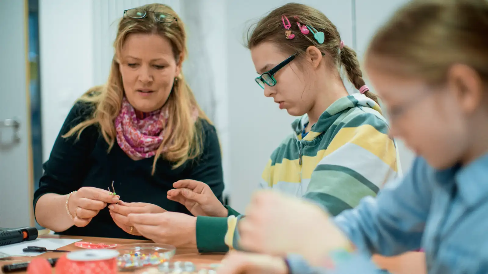 Eine Frau mit zwei Kindern an einem Tisch beim Basteln