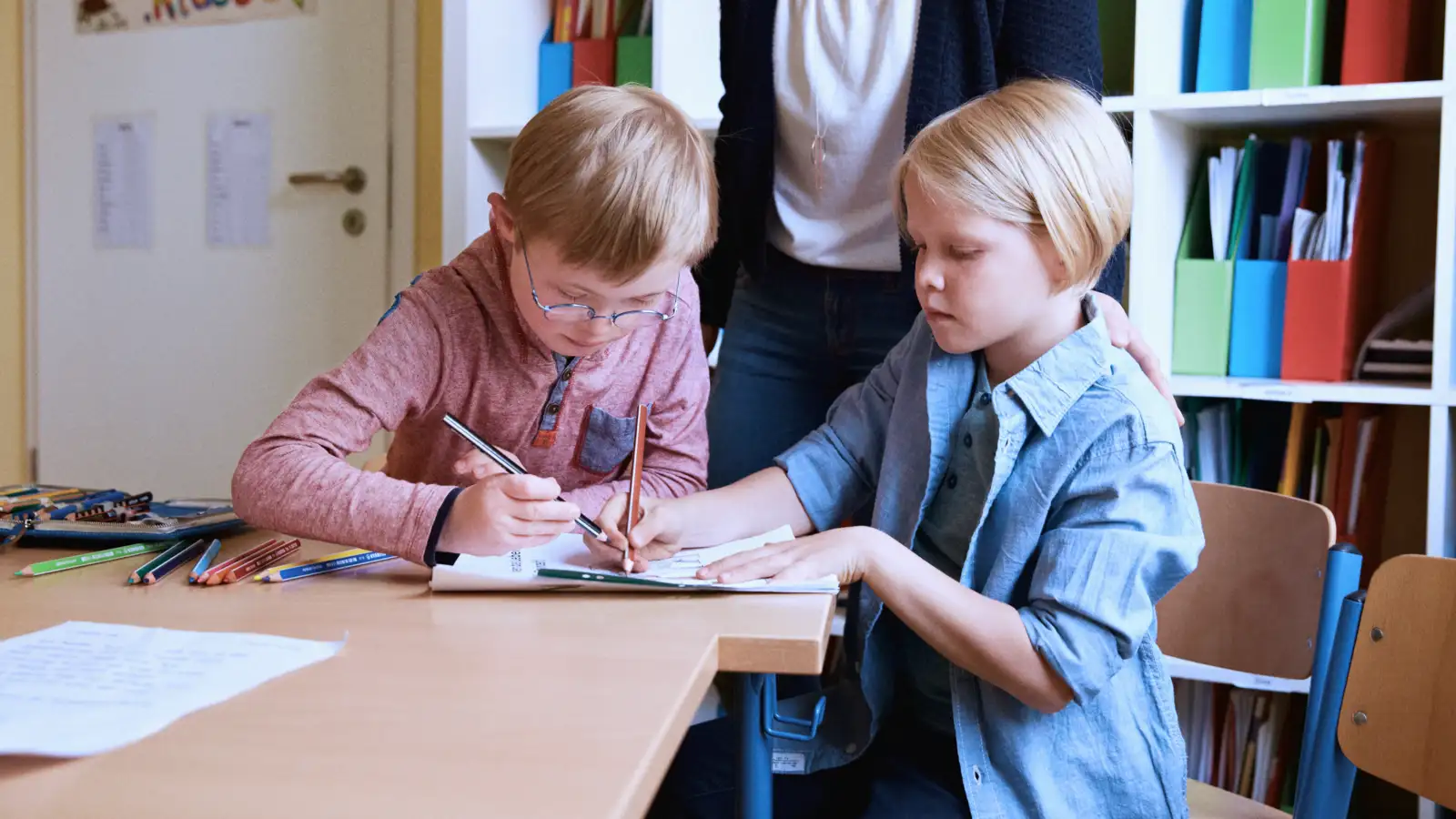 Zwei Kinder lernen gemeinsam in der Schule an einem Tisch.