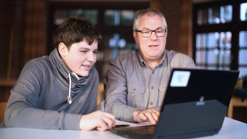 Ein Junge und ein Mann vor einem Laptop