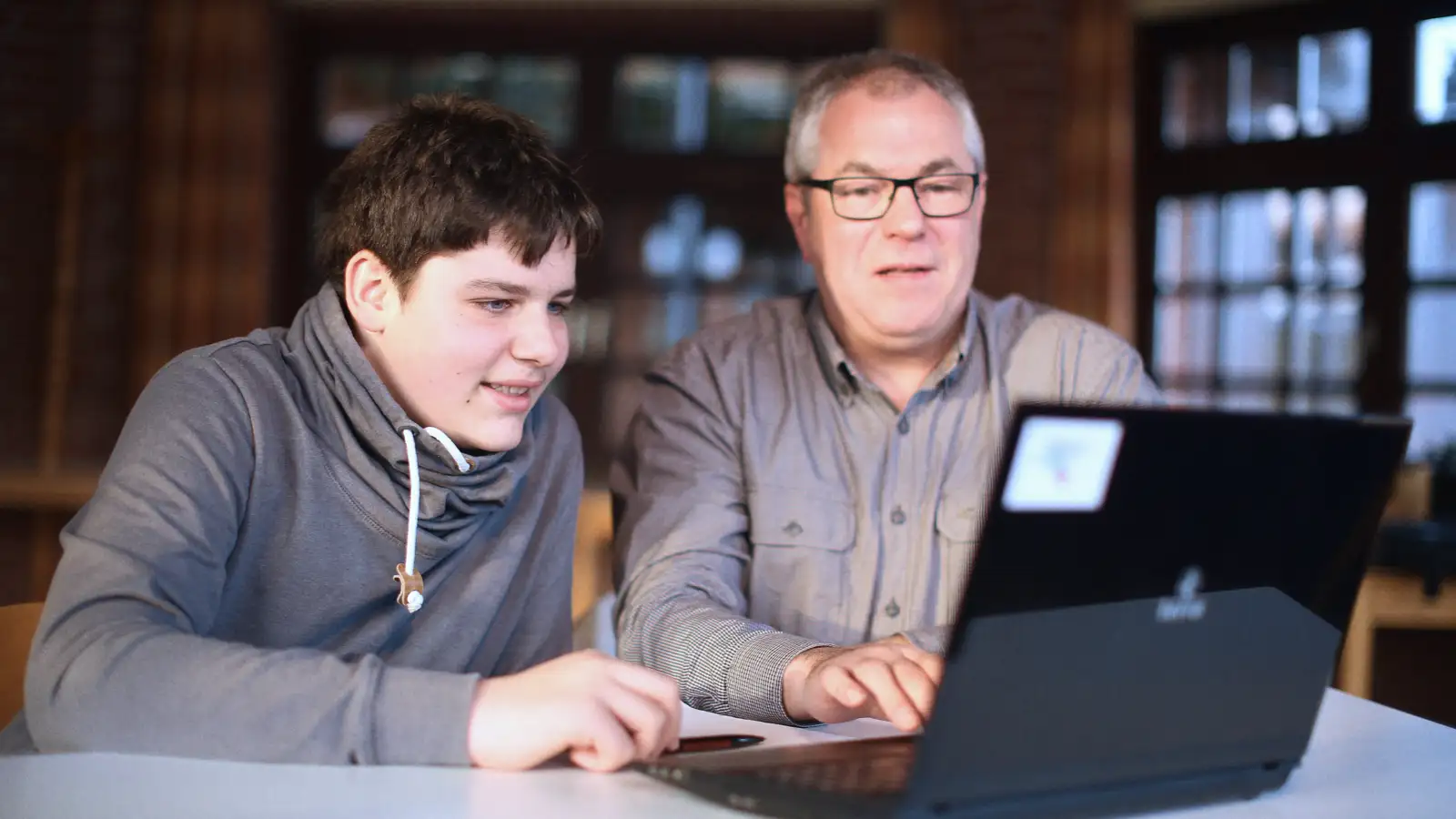 Ein Junge und ein Mann vor einem Laptop