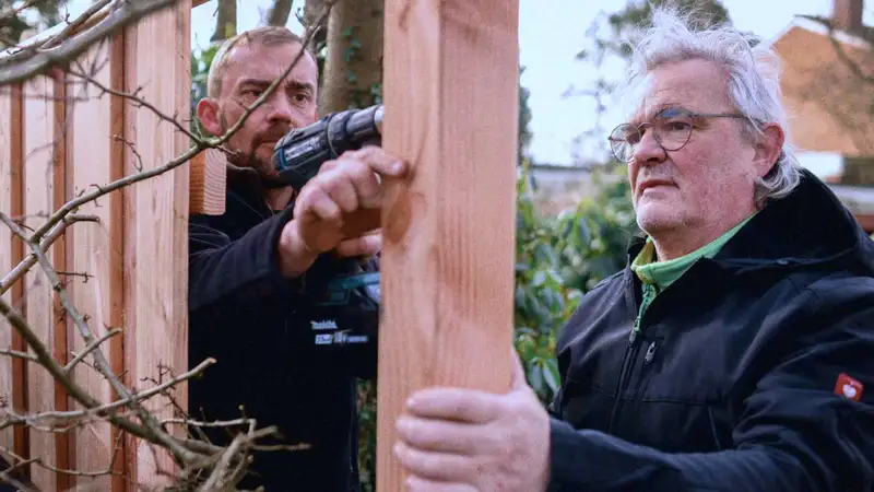 Zwei Männer bauen einen Holzzaun