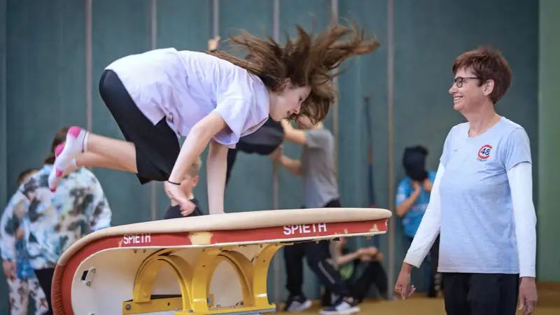 Ein Mädchen mit einer Übungsleiterin in einer Turnhalle bei einer Sprungübung