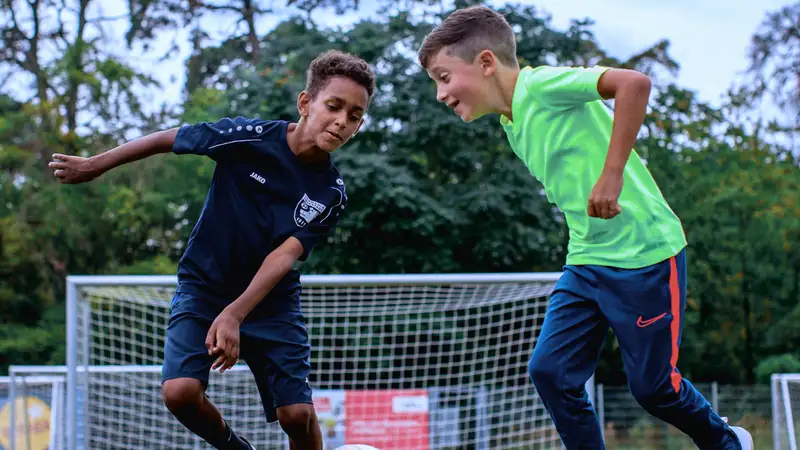 Zwei Fußball spielende Jungen kämpfen um einen Ball.