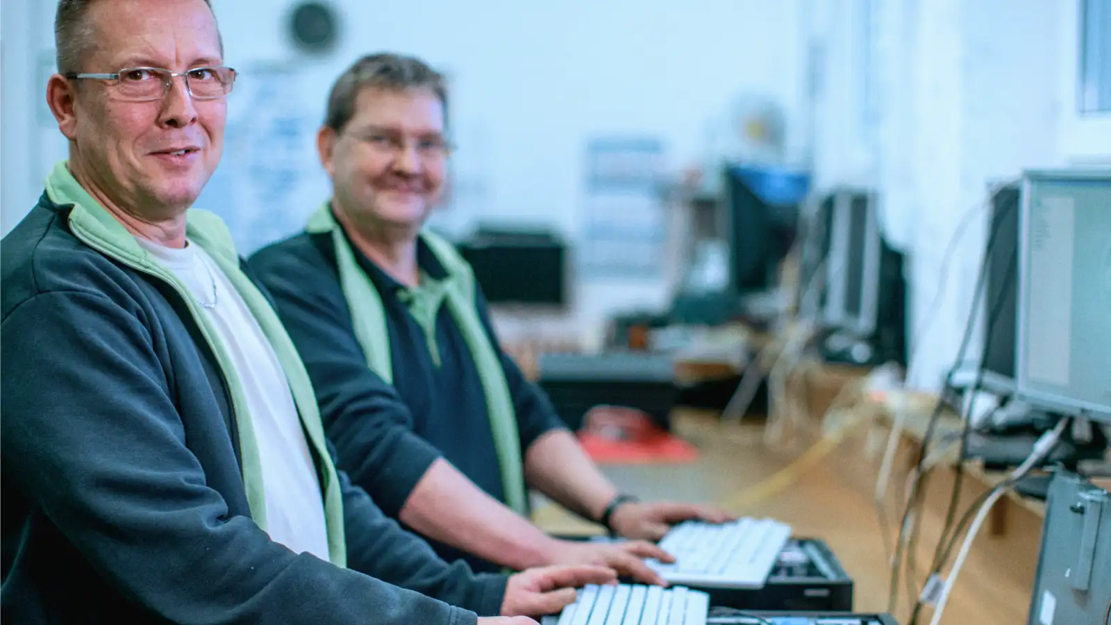 Zwei Männer überprüfen oder reparieren technische Geräte.