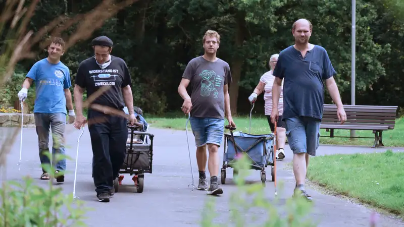 Eine Gruppe von Menschen bei einer Aufräumaktion im Park.