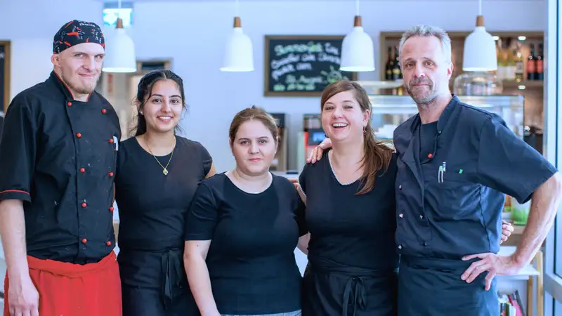 Eine Gruppe von fünf Personen, die in einem Café arbeiten.