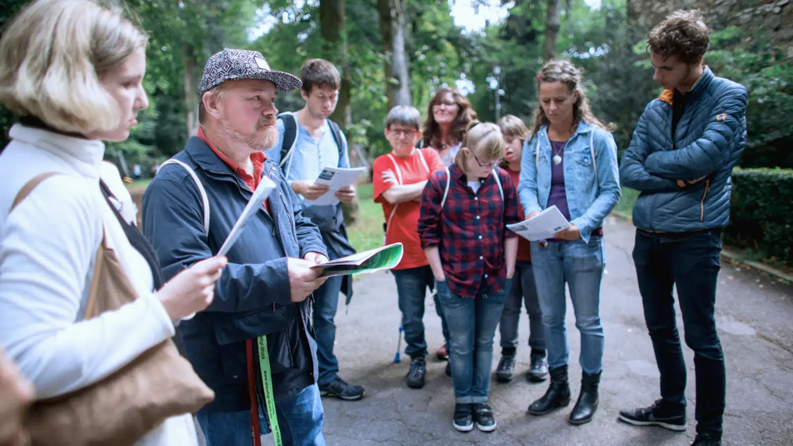Mehrere Menschen im Freien lesen Informationen, die sie in den Händen halten.