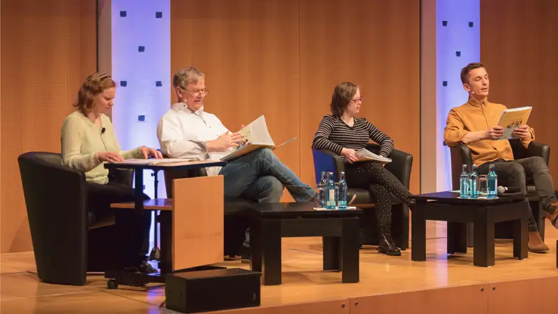 Vier Personen auf einer Bühne bei einer Podiumsdiskussion