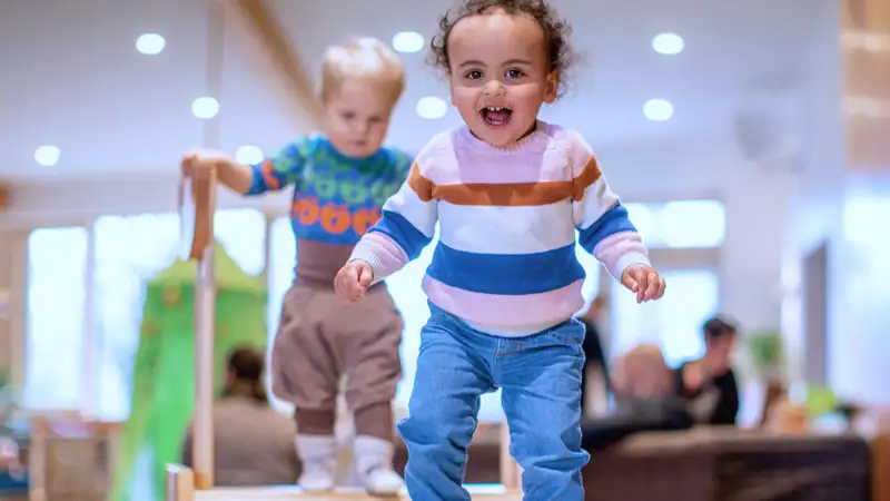 Zwei Kleinkinder klettern im Innenbereich einer Kita