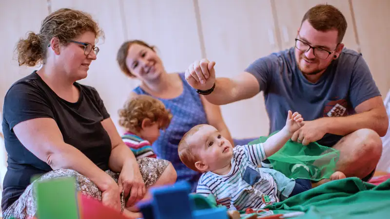 Mehrere Eltern mit ihren Kindern in einer Kleinkind-Spielgruppe