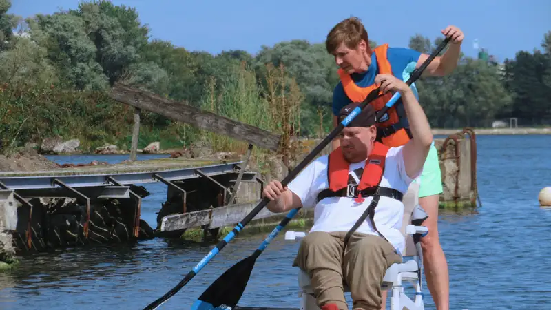 Eine stehende Frau und ein sitzender Mann beim gemeinsamen Stand-up Paddling auf dem Wasser.