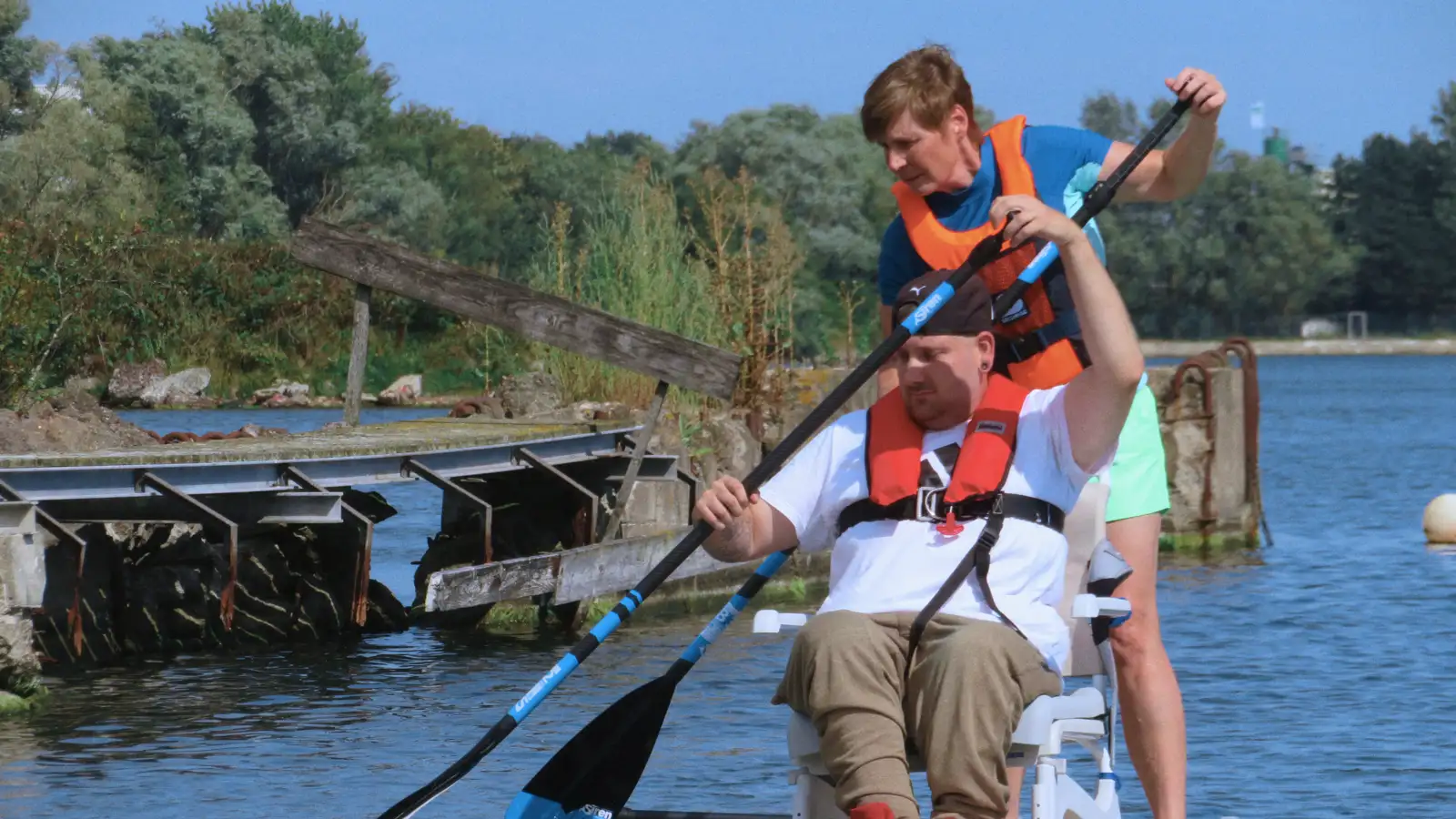 Eine stehende Frau und ein sitzender Mann beim gemeinsamen Stand-up Paddling auf dem Wasser.