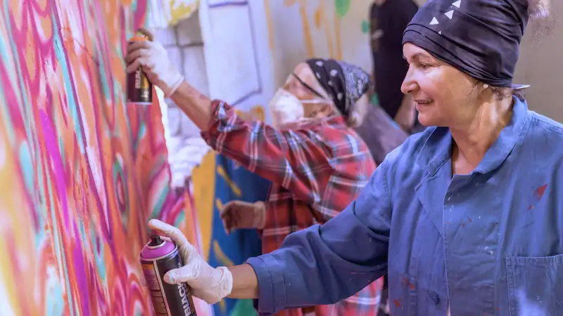 Zwei ältere Frauen sprühen Graffiti in einem Atelier.