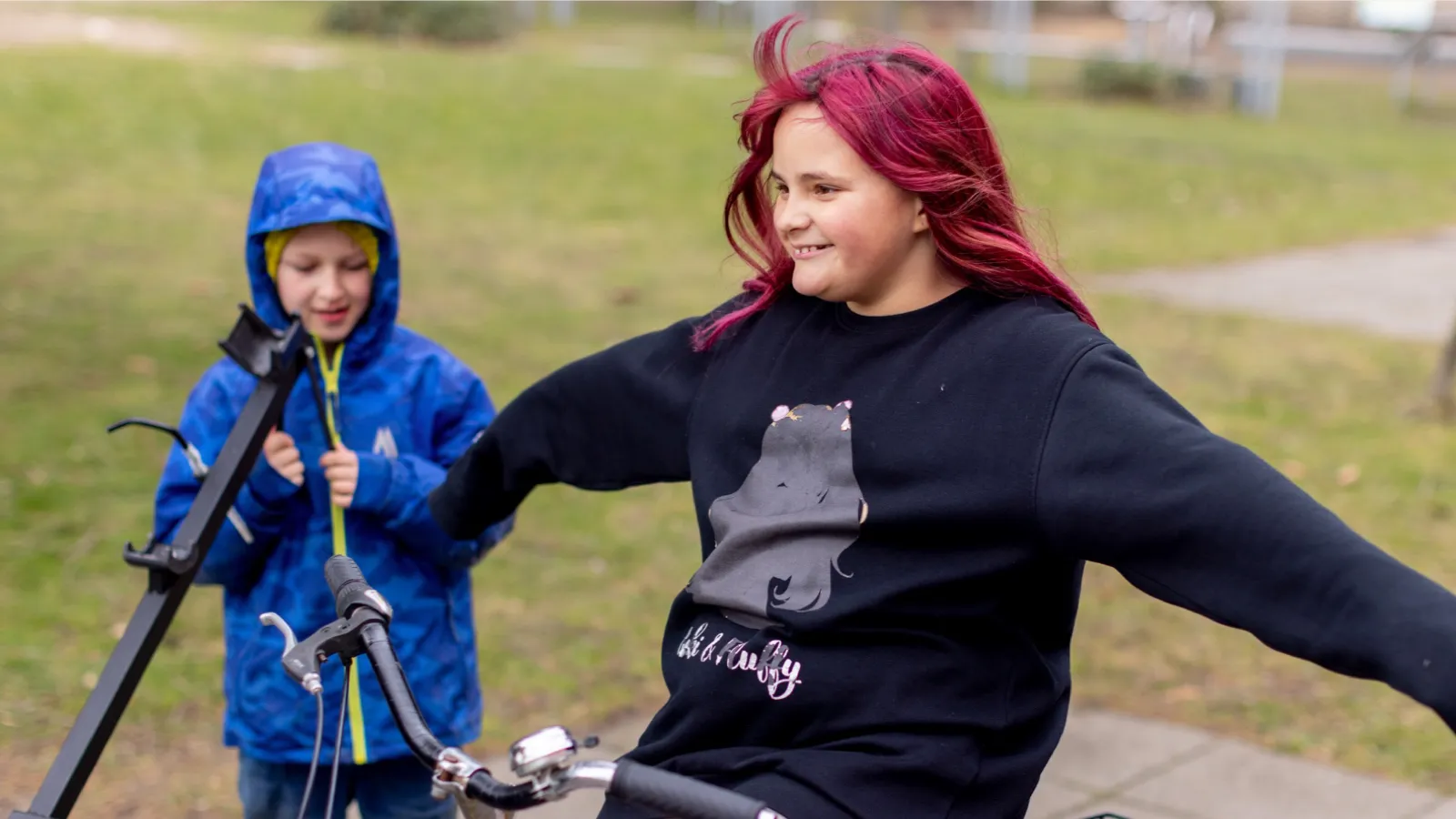 Eine Jugendliche mit bunten Haaren fährt freihändig Fahrrad.