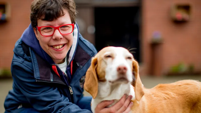 Eine lächelnde Frauß mit einem großen weiß-braunen Hund