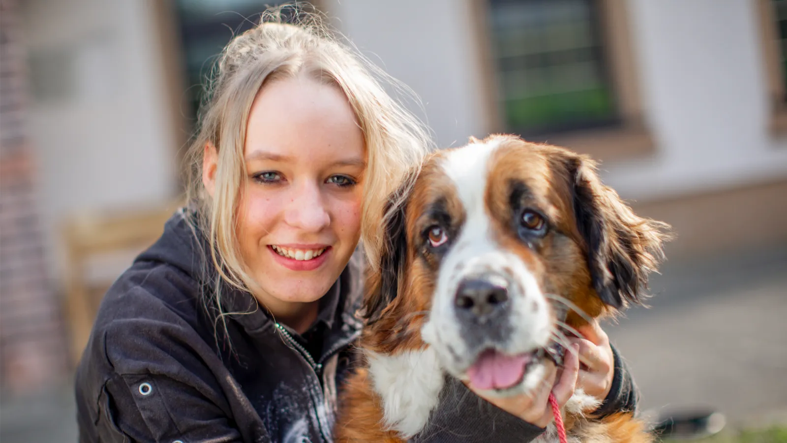 Eine lächelnde junge Frau mit einem Berner Sennhund