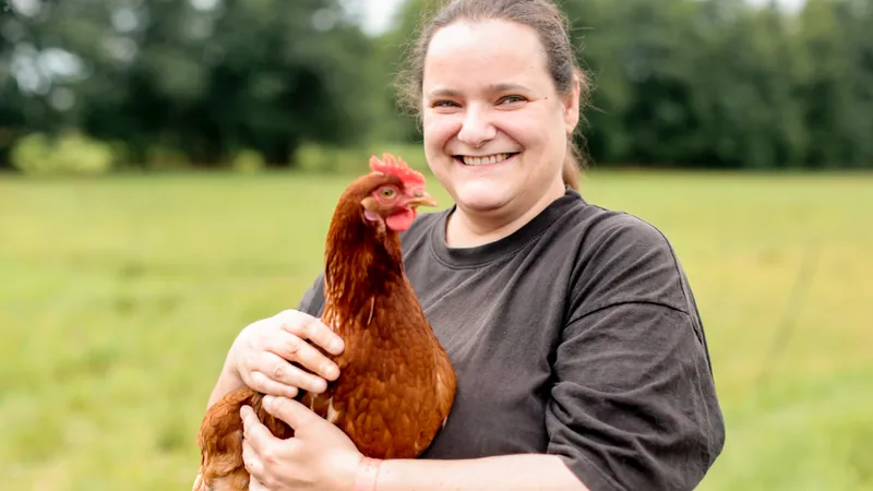 Eine lächelnde Frau mit einem Huhn im Arm