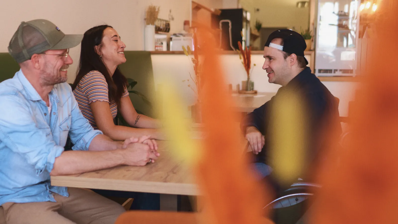 Eine Frau und zwei Männer unterhalten sich in einem Café