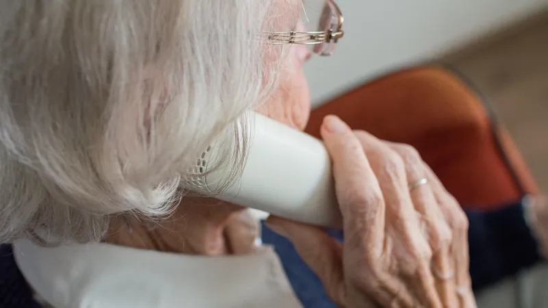 Eine ältere Frau hält einen Telefonhörer ans Ohr