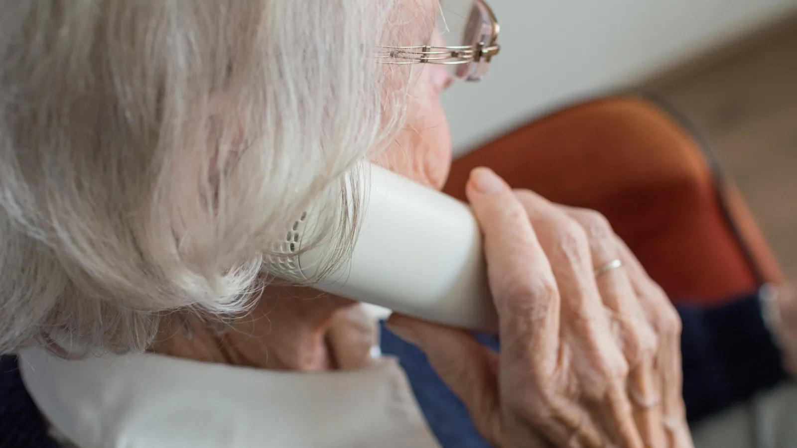 Eine ältere Frau hält einen Telefonhörer ans Ohr