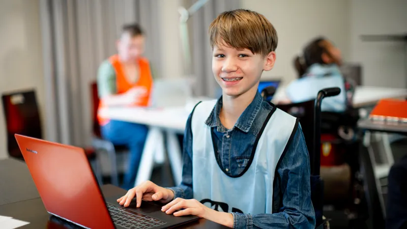 Ein Junge im Rollstuhl arbeitet an einem Laptop