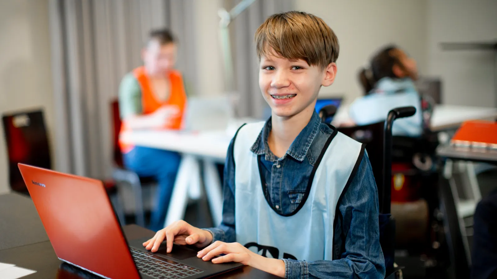 Ein Junge im Rollstuhl arbeitet an einem Laptop