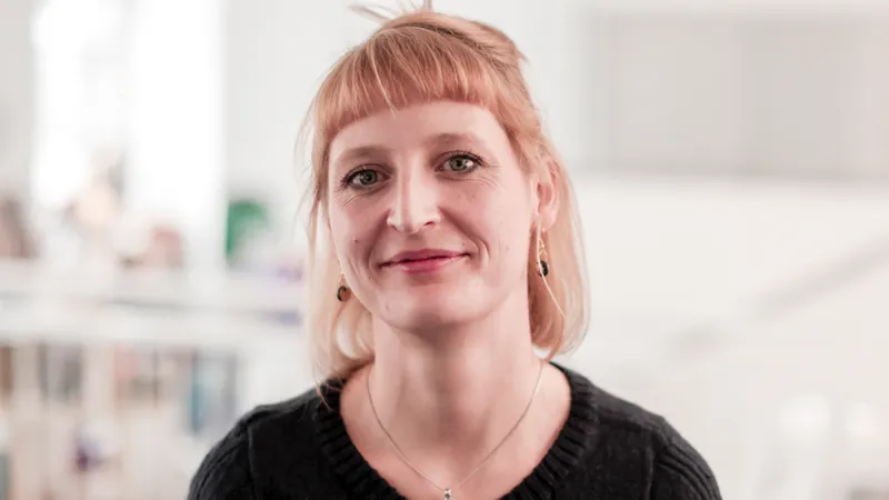 Eine junge Frau blickt lächelnd in die Kamera