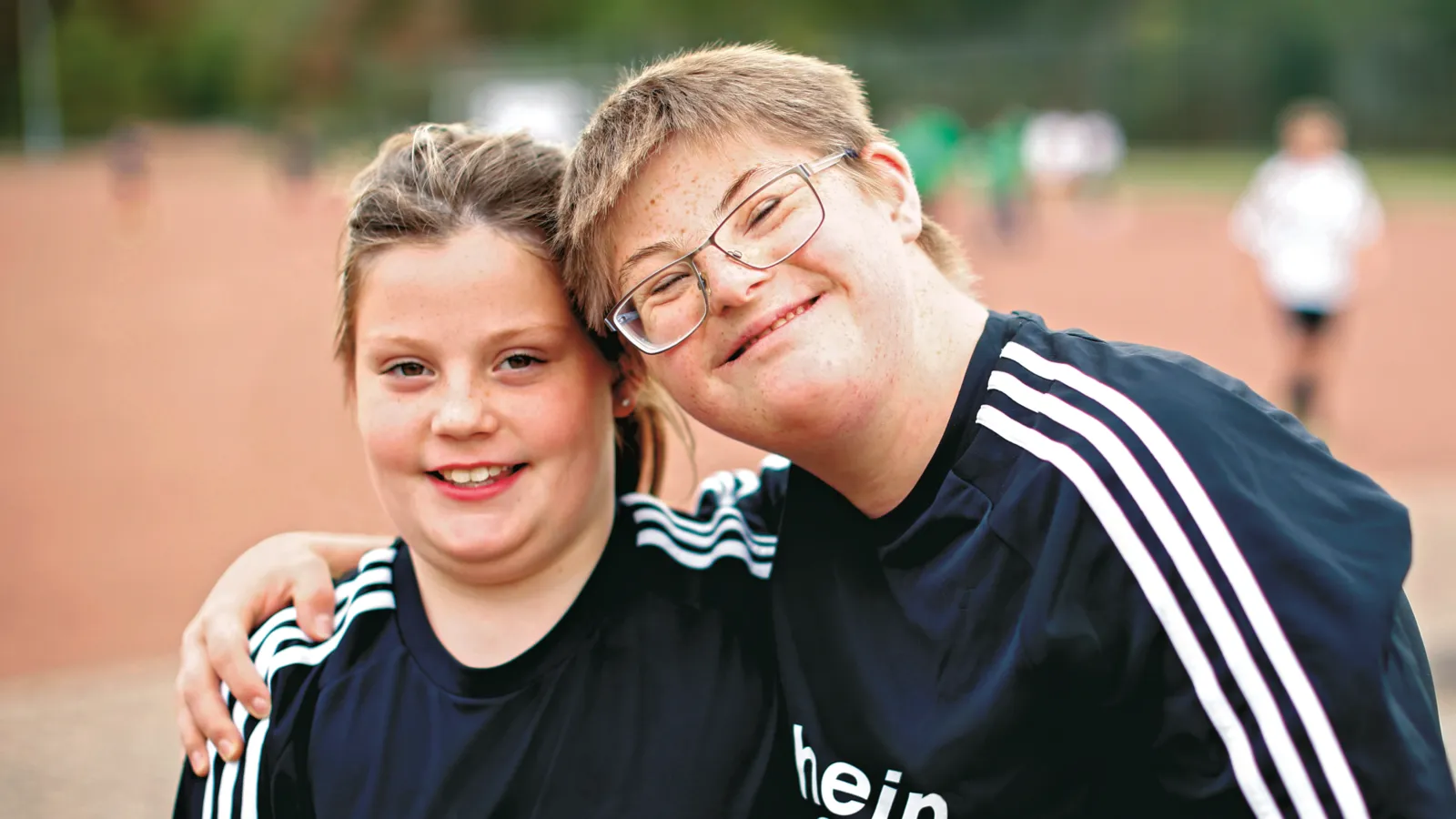 Zwei Kinder in Sporttrikots lächeln in die Kamera