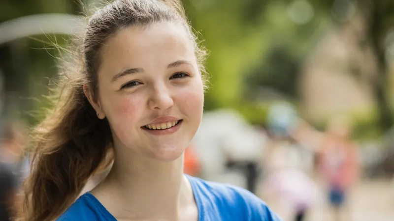 Eine Jugendliche im Freien lächelt in die Kamera