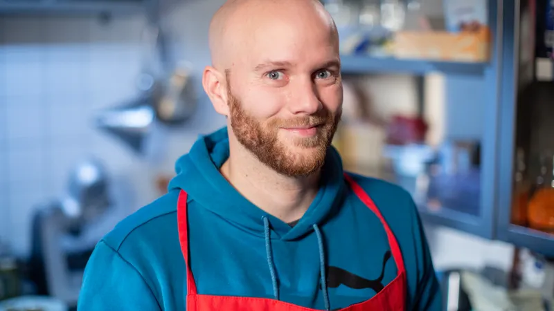 Ein Mann mit einer roten Schütze vor dem Hintergrund einer Küche