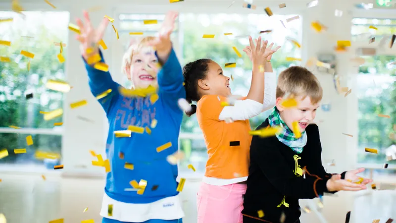Drei Kinder werfen goldenes Konfetti in die Luft