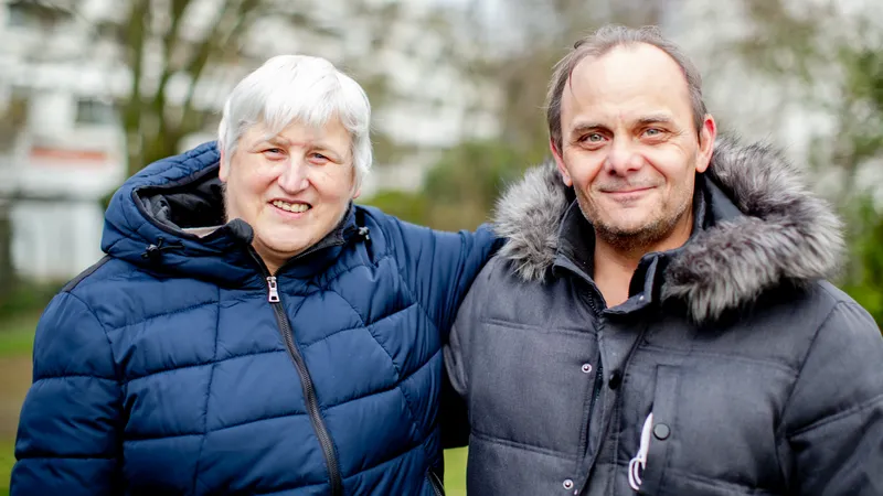 Eine ältere Frau hält ihren Arm um einen Mann