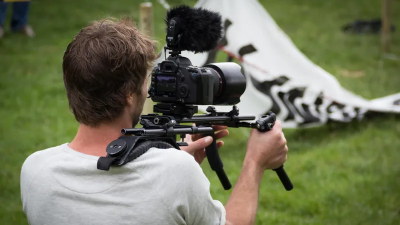 Rückansicht eines Mannes, der eine Videokamera auf der Schulter trägt