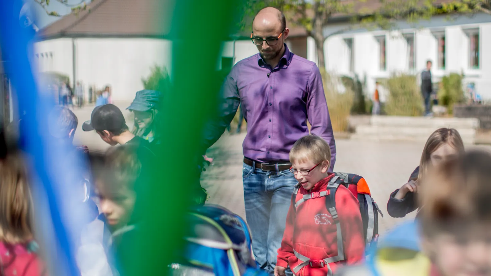 Ein Mann mit mehreren Kindern auf einem Schulhof