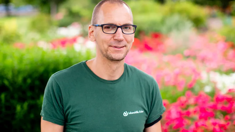 Ein Mann vor dem Hintergrund eines Blumenbeetes