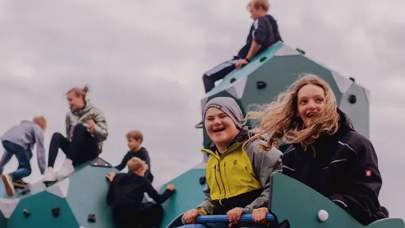 Eine Gruppe lachender Kinder auf Spielgeräten auf einem Spielplatz