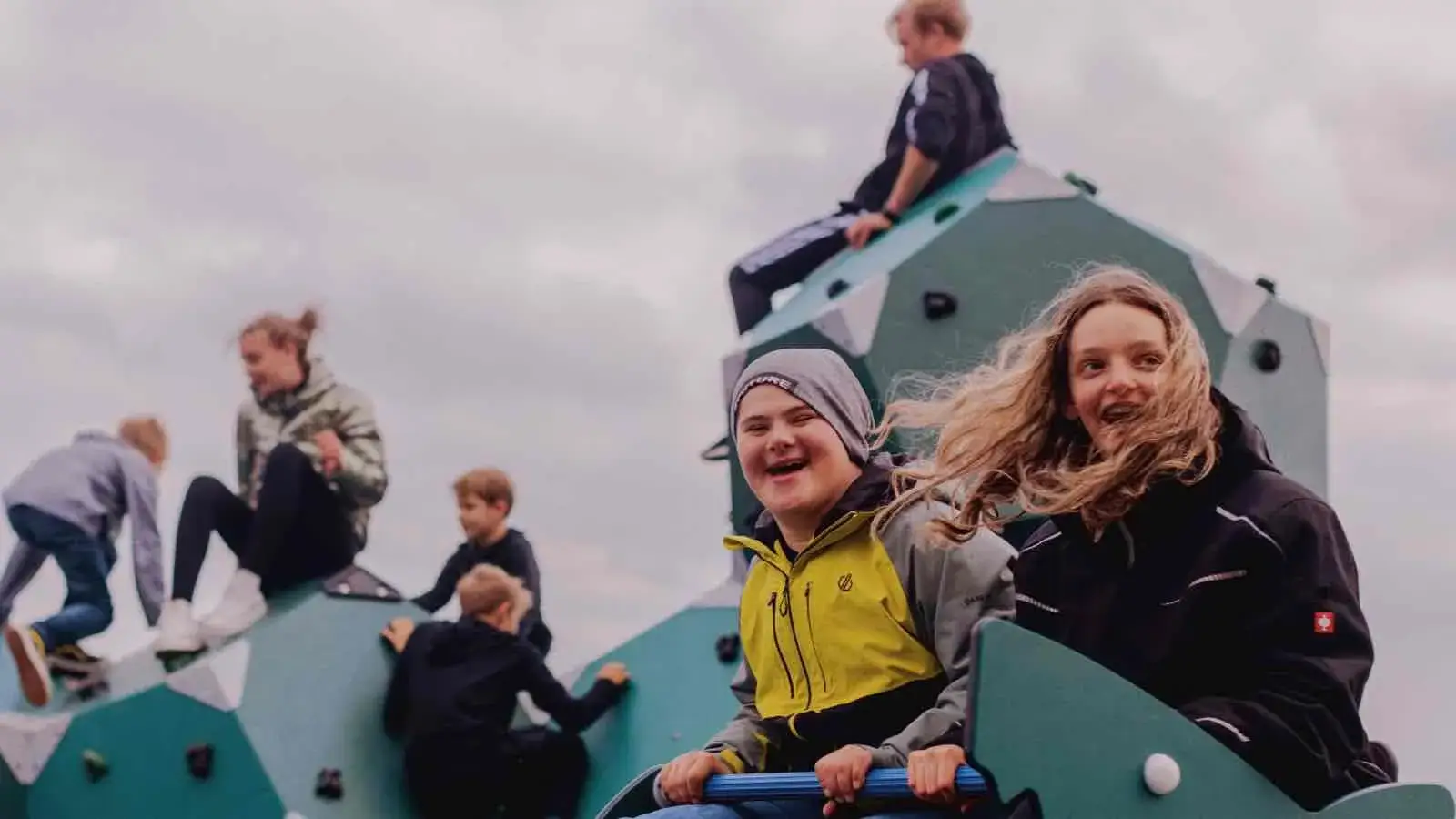 Eine Gruppe lachender Kinder auf Spielgeräten auf einem Spielplatz