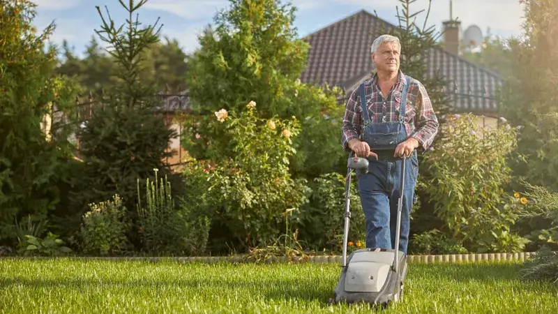 Ein Mann mit Rasenmäher im Garten