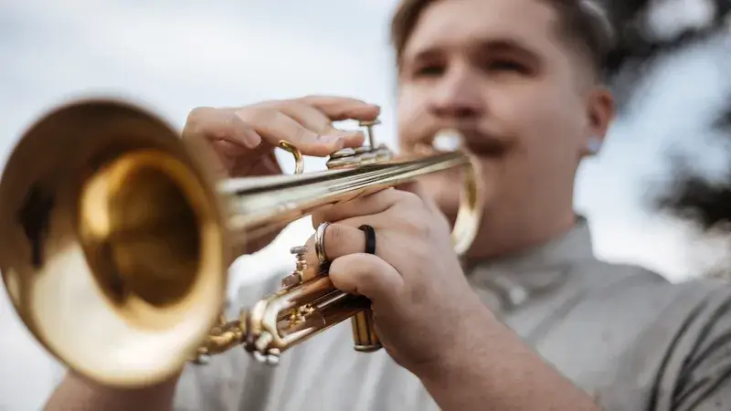 Ein junger Mann spielt im Freien Trompete-