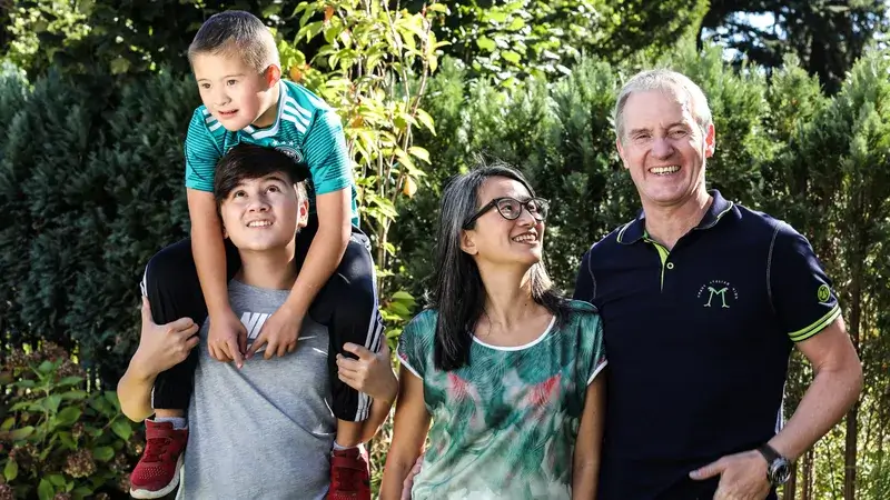 Eine Familie mit Frau, Man und zwei Kindern im Freien vor einer grünen Hecke