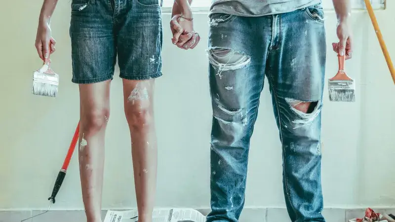 Zwei Menschen mit Pinsel in der Hand und verschmierter Kleidung, dargestellt von der Hüfte abwärts