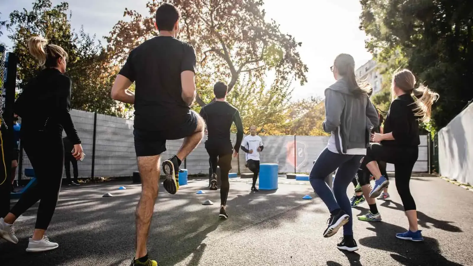 Eine Gruppe von Jugendlichen und ihrem Trainer machen Aufwärmübungen im Freien.